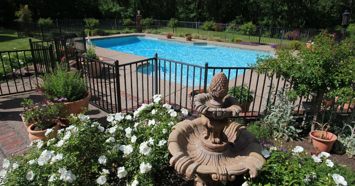 gated pool with landscaping and fountain