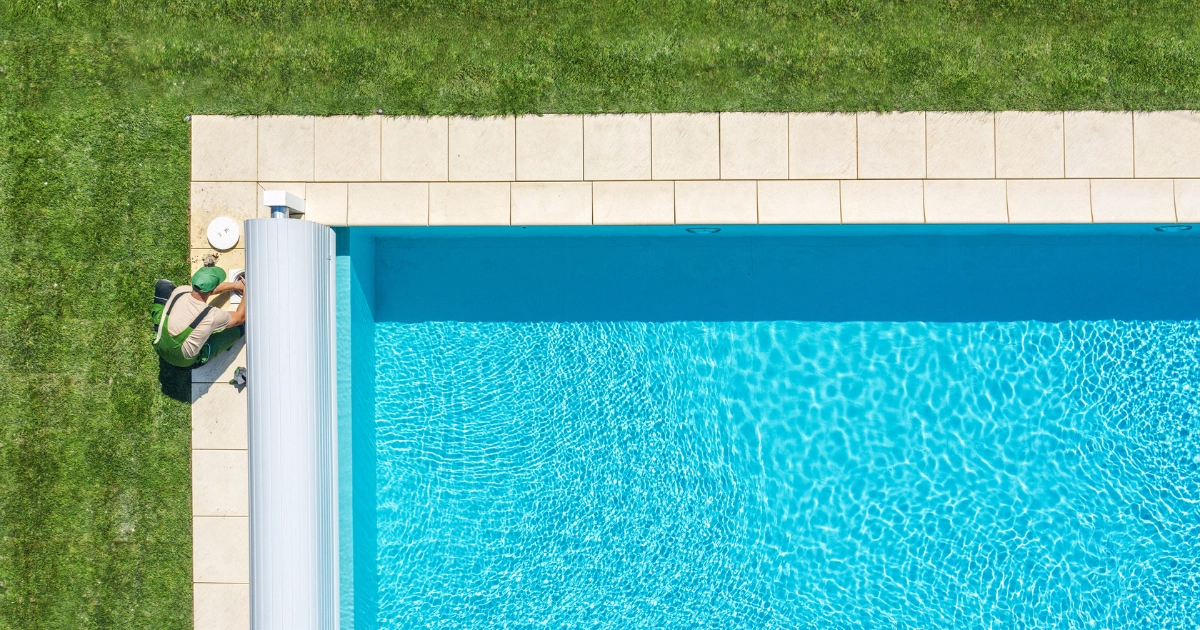 Man cleaning skimmer on pool with cover
